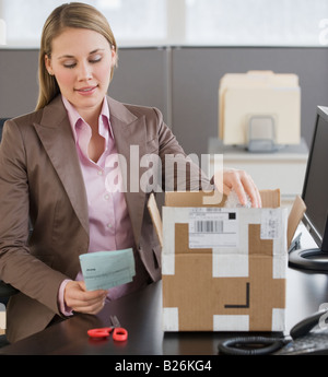 Businesswoman opening package Stock Photo