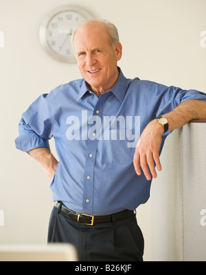 Senior businessman leaning on cubicle wall Stock Photo