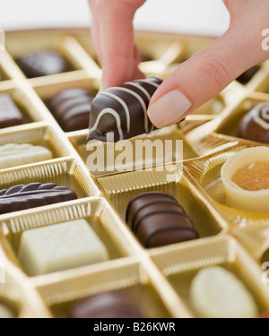 Woman holding chocolate over box of chocolates Stock Photo
