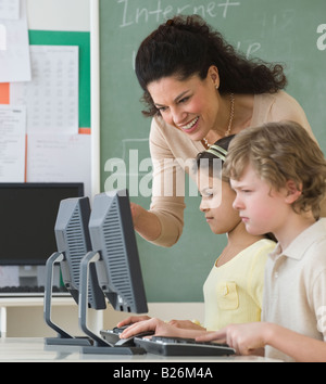 Hispanic teacher helping students with computers Stock Photo