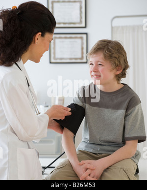 Hispanic female doctor taking child’s blood pressure Stock Photo