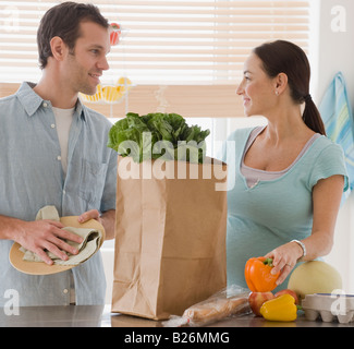 Pregnant Hispanic couple unpacking groceries Stock Photo