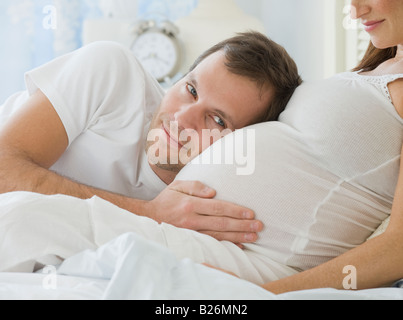 Hispanic man resting head on pregnant wife Stock Photo