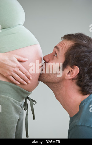 Hispanic man kissing pregnant wife’s belly Stock Photo