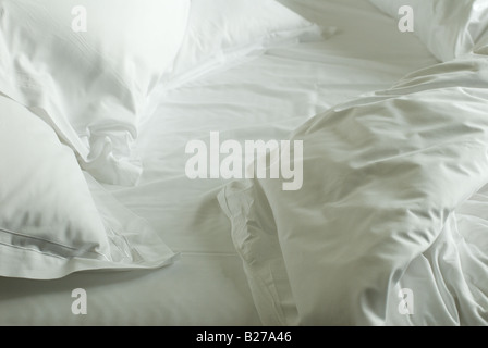 Rumpled white sheets and pillows in the morning light. Stock Photo