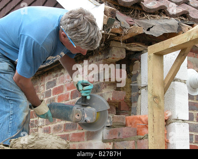 builder / construction worker working on a brick wall cementing bricks in Stock Photo