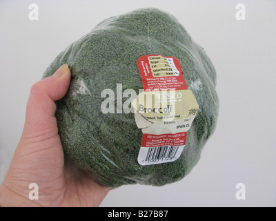 woman holding pre packed plastic packaging on broccoli from a supermarket Stock Photo