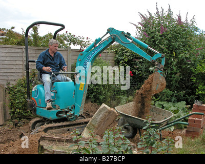 builder / construction worker using a Dowling & Rabbit mini excavator digger to remove soil prior to working on an extension Stock Photo