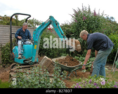 builder / construction worker using a Dowling & Rabbit mini excavator digger to remove soil prior to working on an extension Stock Photo