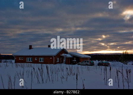 A red brick house covered in snow with three cars parked in front in the Finnish Lapland Stock Photo