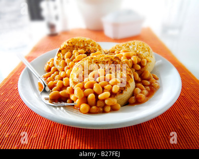 Baked beans on crumpets served as a meal on a white plate in a table setting Stock Photo