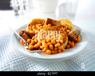 Baked beans and sausages on crumpets served as a meal on a white plate ...