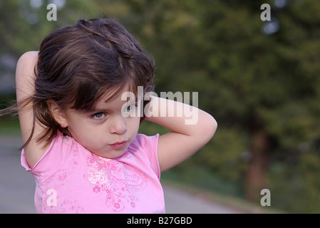 4-5 years old girl in pink shirt fixing her hair Stock Photo