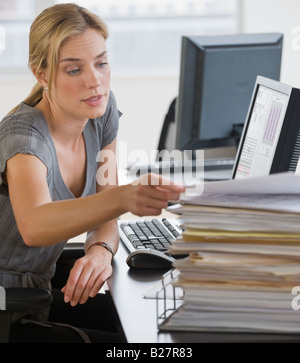 Businesswoman with stack of paperwork on desk Stock Photo