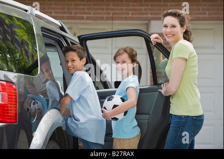 Mother and children getting into car with soccer ball Stock Photo