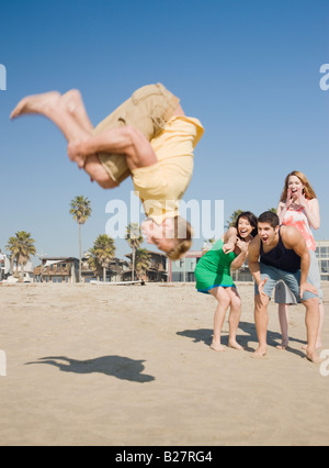 Man doing back flip on beach Stock Photo