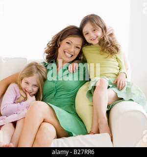 Mother and daughters hugging on sofa Stock Photo