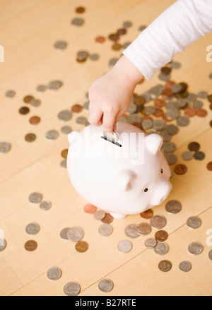 Child putting coin in piggy bank Stock Photo