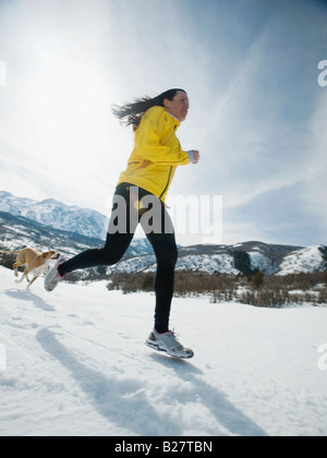 Woman and dog running in snow