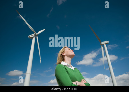 Low angle view of woman and wind turbines Stock Photo