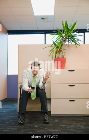 Frustrated businessman looking at cell phone Stock Photo