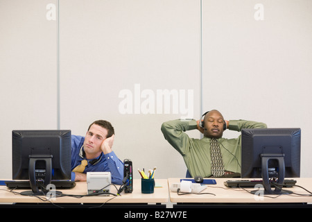 Multi-ethnic businessmen sitting at desks Stock Photo