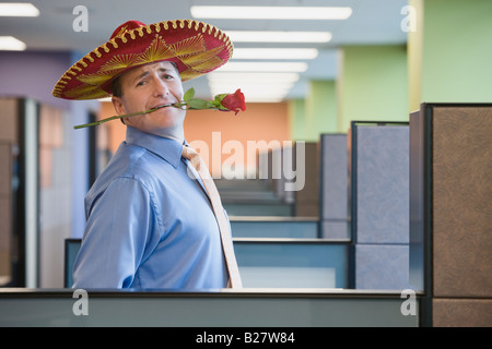 Businessman wearing sombrero and holding rose in teeth Stock Photo