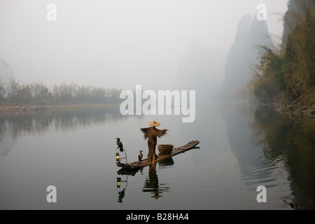 Fisherman in Suoyi coat and coolie hat fishes with cormorants on Li River near Guilin China Stock Photo