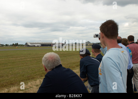 Spectators watching an aircraft landing whilst taking a picture on his small digital camera Farnborough Air Show 2008 Stock Photo