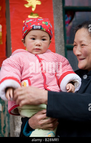 Woman carries granddaughter in Fuli Xingping China has a one child family planning policy to limit population Stock Photo