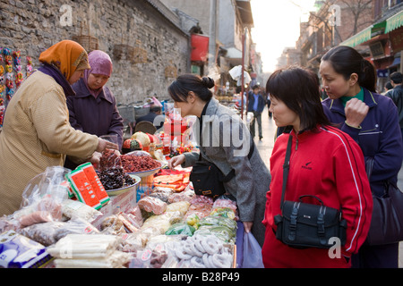 Chinese women selling souvenirs and food at market stall in Moslem district of Xian China Stock Photo