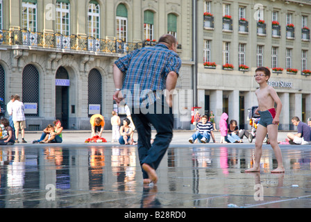 Father and son playing in the fountain in front of the House of Parliament, Bern, Switzerland. Stock Photo