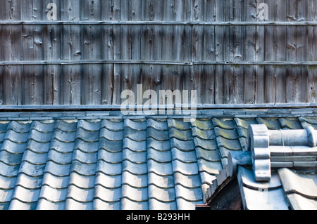 Traditional Japanese ceramic roof tiles with wooden planking and a roof apex in the foreground. Stock Photo