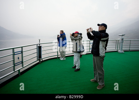 Tourists take photographs from the deck of a Victoria Line Cruise Ship Yangtze River China Stock Photo