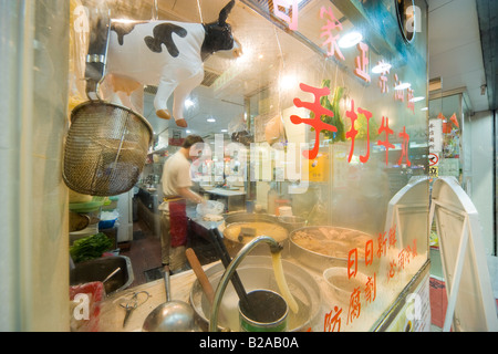 Exterior of noodle shop restaurant on Tung Choi Street in Mongkok, Kowloon, Hong Kong, China. Inflatable cow in shop window. Stock Photo