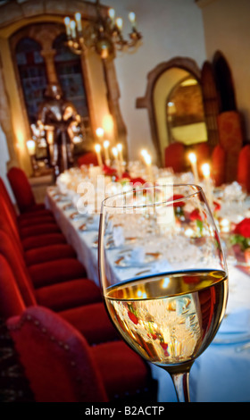 White wine glass in foreground of a formal prepared candlelit luxury dinner banquet party table. Wine pairing tasting Stock Photo