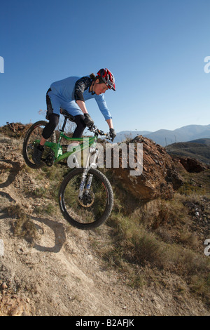 Female Mountain Biker Rides over Rocks in Sierra Nevada, Spain Stock Photo