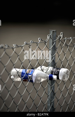 empty plastic water bottles pushed in chain link fence Stock Photo