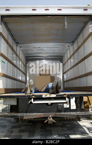 Feet of young couple relaxing in back of moving truck Stock Photo