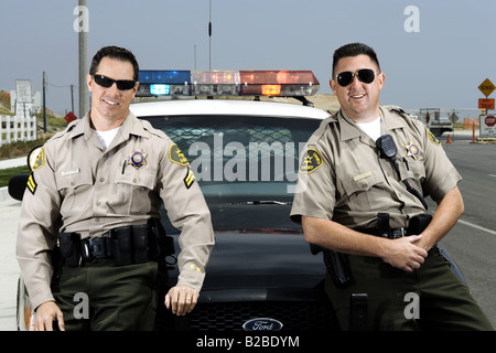 Two police officers standing in front of police car