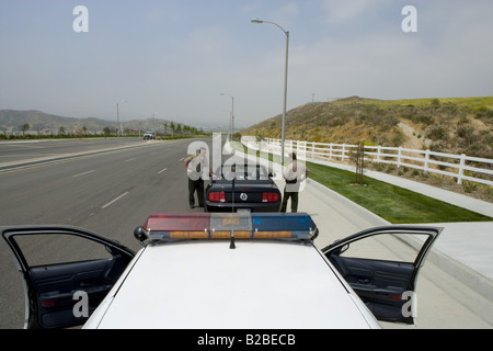 Two police officers approaching man driving Mustang Stock Photo