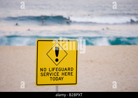 Sydney Bronte Beach in winter with sign No Lifeguard Service here today. Swimmers and surfers in the background. NSW Australia. Stock Photo