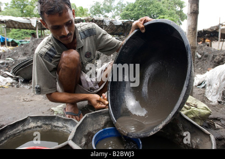 Many slum inhabitants live from recycling old industrial waste. Here daily paid workers wash poisonous industrial slag searchin Stock Photo