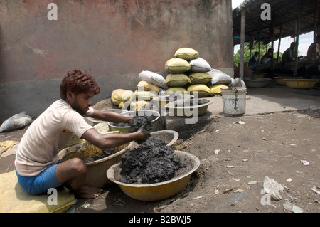 Many slum inhabitants live from recycling old industrial waste. Here daily paid workers wash poisonous industrial slag searchin Stock Photo