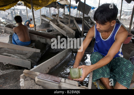 Many slum inhabitants live from recycling old industrial waste. Here daily paid workers are washing poisonous industrial slag s Stock Photo