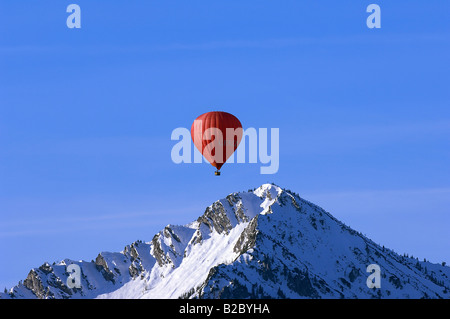 Red hot air balloon floats over the peak of Mt. Ochsenkamp, Montgolfiade, Tegernsee Mountains, Bad Wiessee, Bavaria Stock Photo