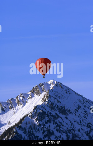 Red hot air balloon floats over the peak of Mt. Ochsenkamp, Montgolfiade, Tegernsee, Bad Wiessee, Bavaria, Germany, Europe Stock Photo