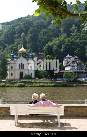 Pensioners sitting on a bench looking at the River Lahn, the Russian Church behind, Bad Ems, Rhineland-Palatinate Stock Photo