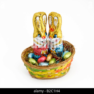 Two Easter bunnies in a basket with chocolate eggs Stock Photo
