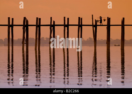 Man carrying a load crossing the U Bein Bridge at sunset, old wooden teak bridge, Mandalay, Myanmar, Southeast Asia Stock Photo